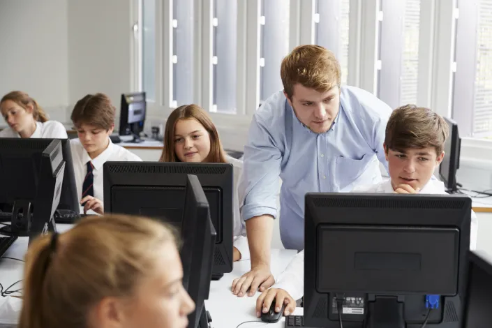 Teacher helping students on computers