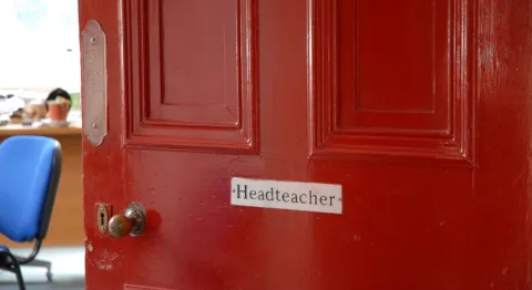 A red door with a headteacher sign on it. 