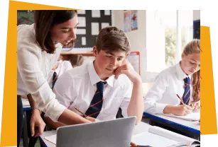 A teacher helping a student on a laptop